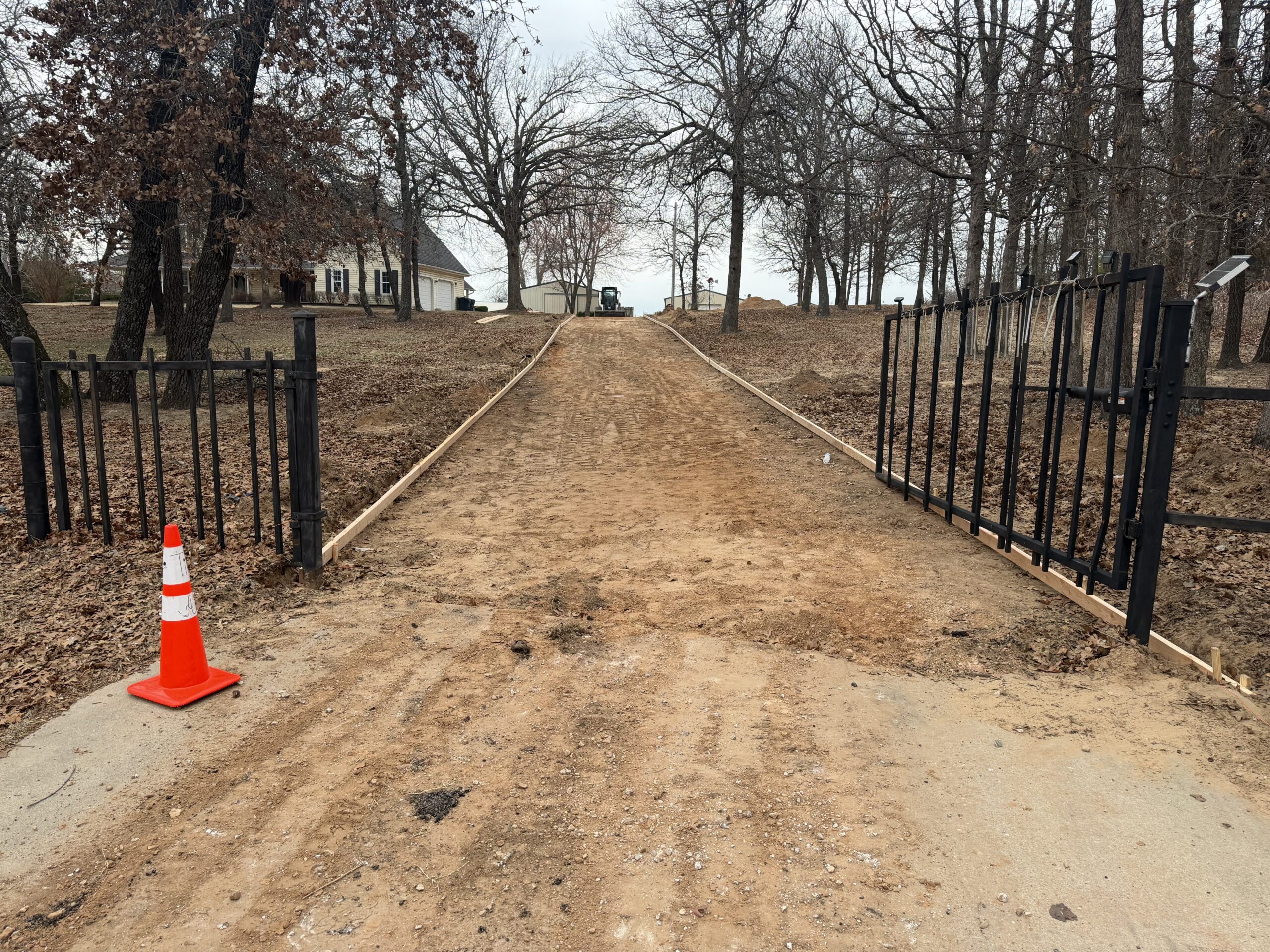 Dirt driveway through open iron gates