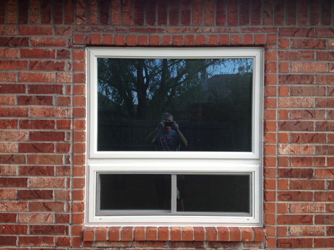 White double window in brick wall reflecting photographer