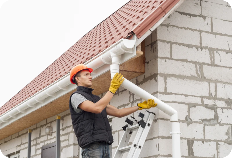 Worker installing house gutter system